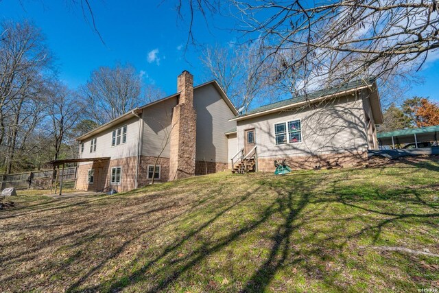 exterior space with entry steps, a lawn, a chimney, and fence