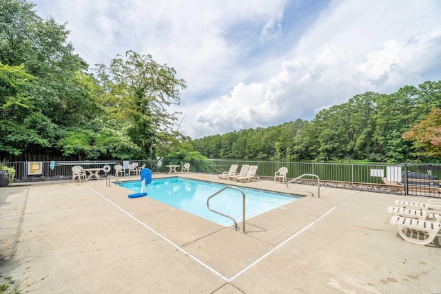 community pool with a patio and fence