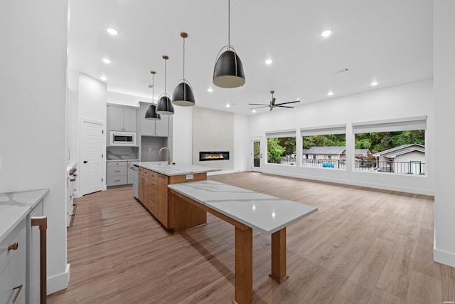 168 Krause Ln Unit A, Hot Springs, AR 71913 - kitchen with white microwave, a glass covered fireplace, an island with sink, ceiling fan, and a sink