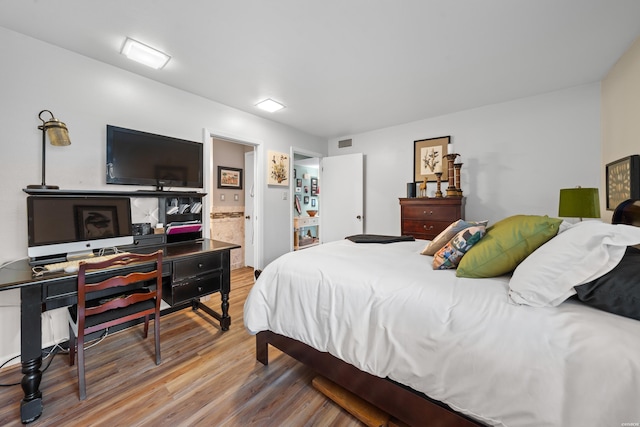 bedroom featuring visible vents, ensuite bath, and wood finished floors