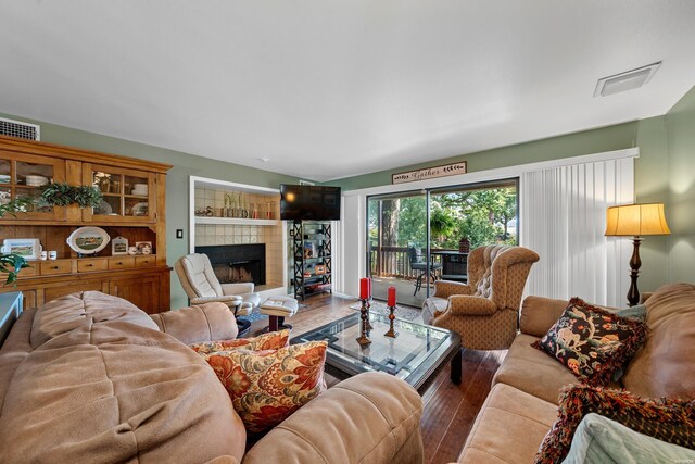 living room with visible vents, wood finished floors, and a tile fireplace