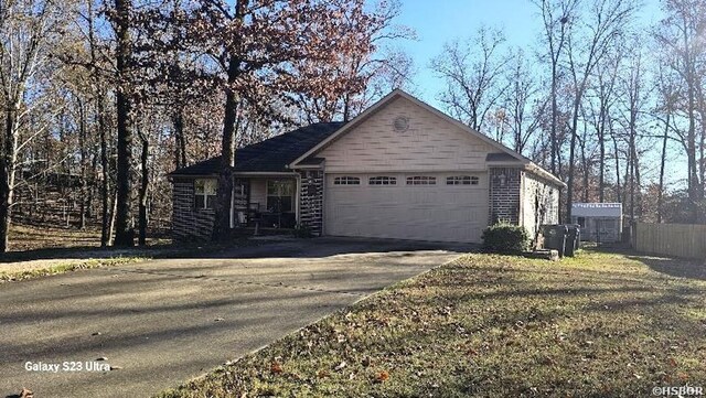 view of front of home with an attached garage, brick siding, fence, driveway, and a front yard