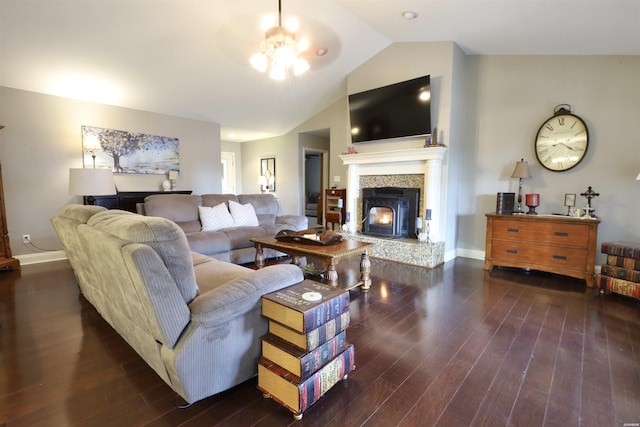 living area featuring dark wood-style flooring, vaulted ceiling, a stone fireplace, and baseboards