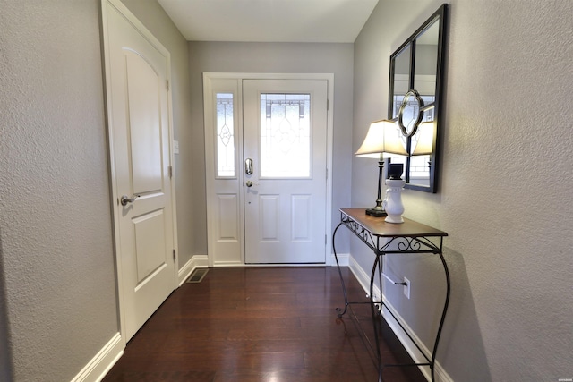 doorway to outside with baseboards, dark wood-style flooring, and a textured wall