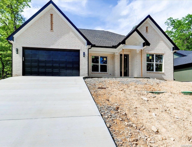 view of front of house featuring an attached garage, brick siding, concrete driveway, and a shingled roof
