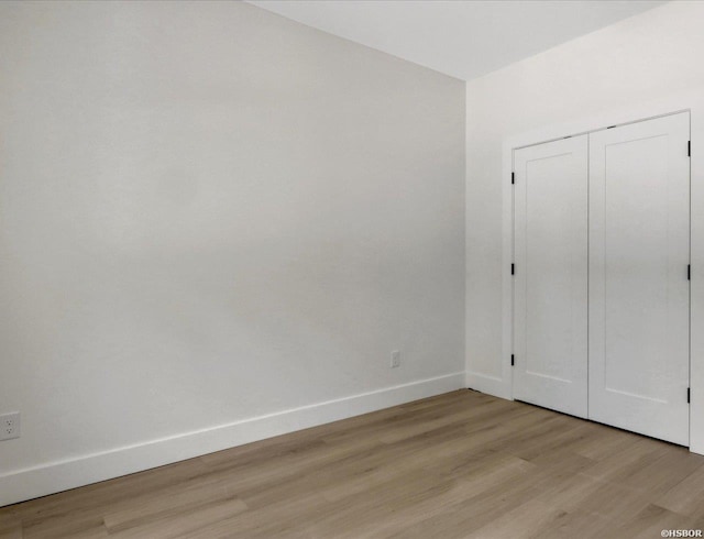 unfurnished bedroom with light wood finished floors, baseboards, and a closet