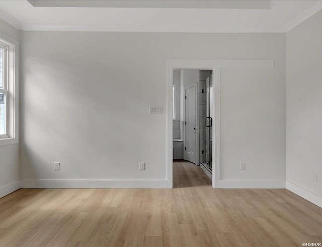 spare room featuring light wood finished floors, plenty of natural light, ornamental molding, and baseboards