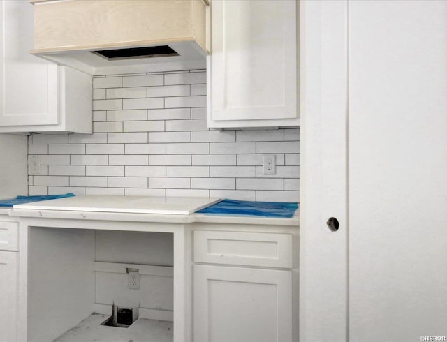 kitchen view of wall chimney exhaust hood, white cabinets, light countertops, and decorative backsplash