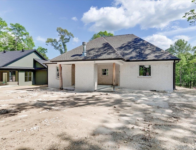 view of front facade featuring brick siding and roof with shingles