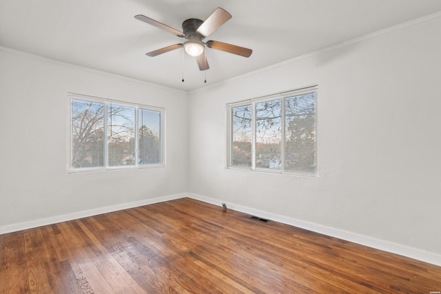 unfurnished room with baseboards, wood-type flooring, visible vents, and crown molding