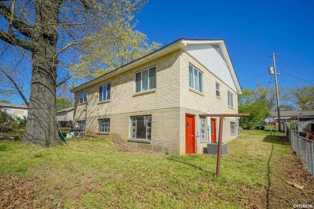 rear view of house featuring central AC, fence, and a lawn