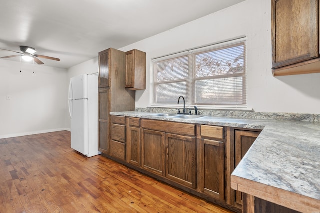 kitchen featuring wood-type flooring, light countertops, a ceiling fan, freestanding refrigerator, and a sink