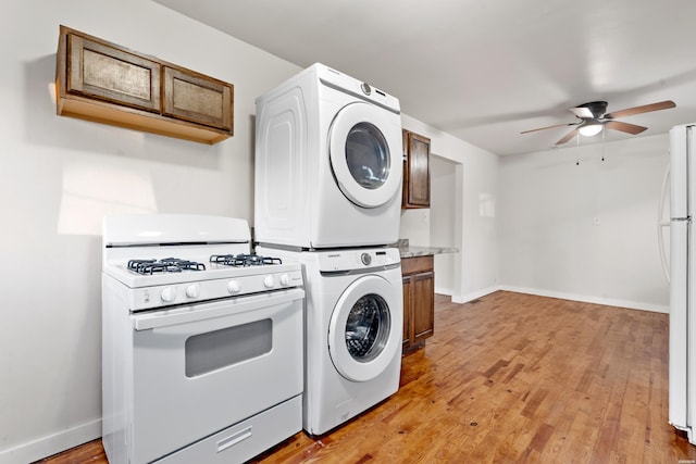 washroom featuring stacked washer and dryer, light wood-type flooring, laundry area, and baseboards