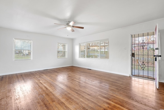 spare room with visible vents, ornamental molding, ceiling fan, wood finished floors, and baseboards