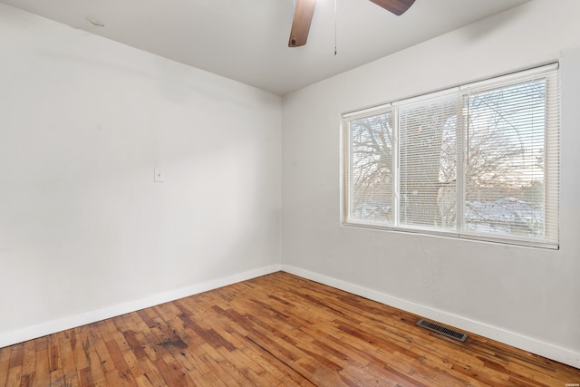 spare room featuring baseboards, plenty of natural light, visible vents, and hardwood / wood-style floors