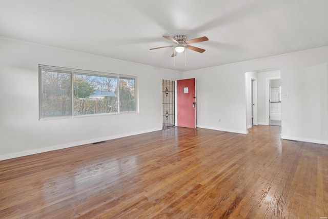 empty room featuring ceiling fan, wood finished floors, visible vents, and baseboards