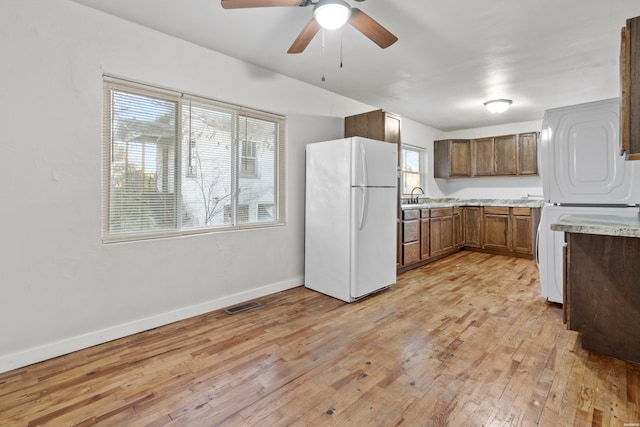 kitchen featuring visible vents, freestanding refrigerator, ceiling fan, light wood-type flooring, and baseboards