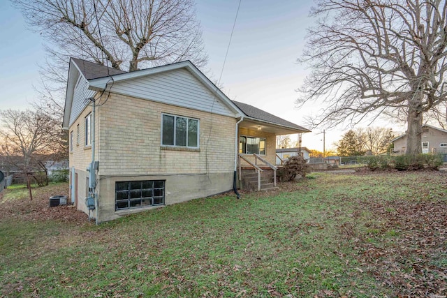 back of property with brick siding, a lawn, and cooling unit