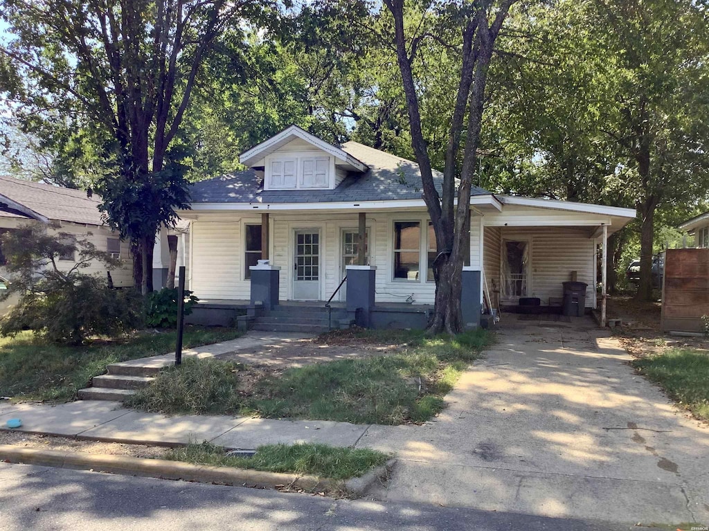 bungalow-style house with a porch, a carport, and concrete driveway