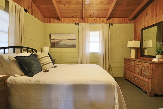 bedroom with dark colored carpet, wood ceiling, concrete block wall, and beam ceiling