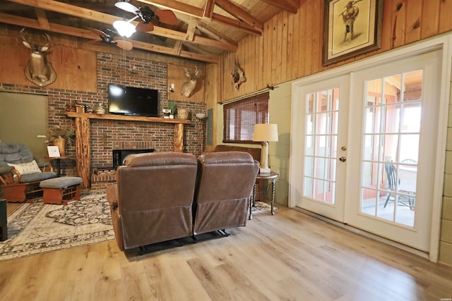 living room featuring light wood-style floors, plenty of natural light, french doors, and wood walls