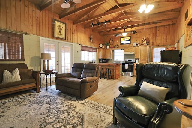 living area featuring wood ceiling, wooden walls, a ceiling fan, and french doors