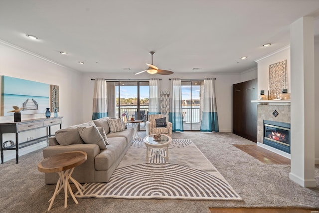 living room featuring baseboards, a tiled fireplace, ornamental molding, carpet floors, and recessed lighting