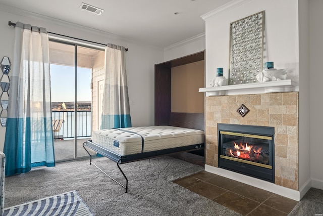 interior space featuring a tile fireplace, a water view, visible vents, baseboards, and crown molding