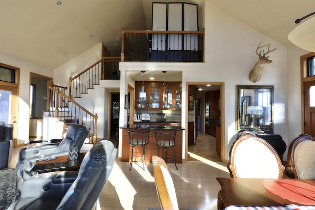 living area with stairs, high vaulted ceiling, wood finished floors, and a wealth of natural light