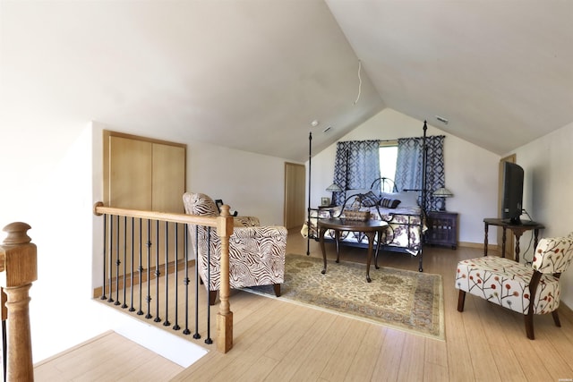 living area with lofted ceiling, visible vents, wood finished floors, and an upstairs landing