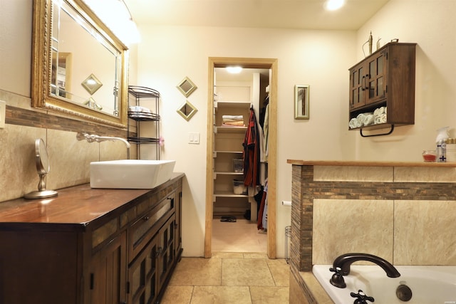 bathroom featuring a walk in closet, a garden tub, tasteful backsplash, vanity, and tile patterned flooring