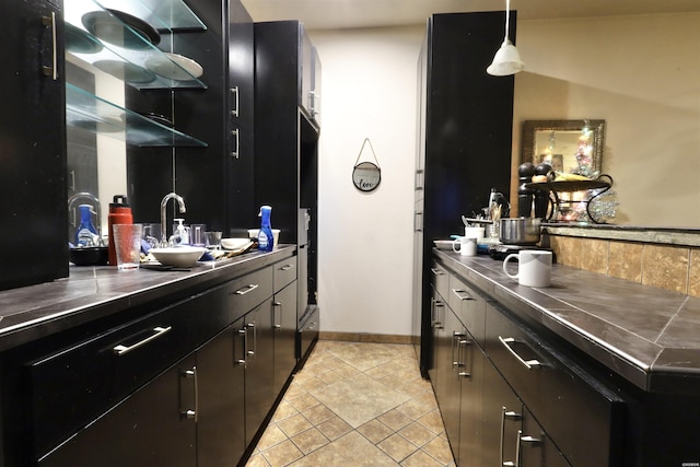 interior space featuring dark cabinetry, dark countertops, a sink, and decorative light fixtures