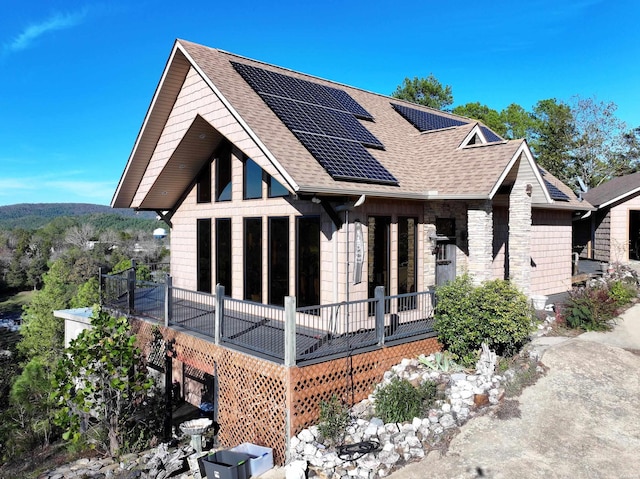 view of front facade featuring roof with shingles and roof mounted solar panels