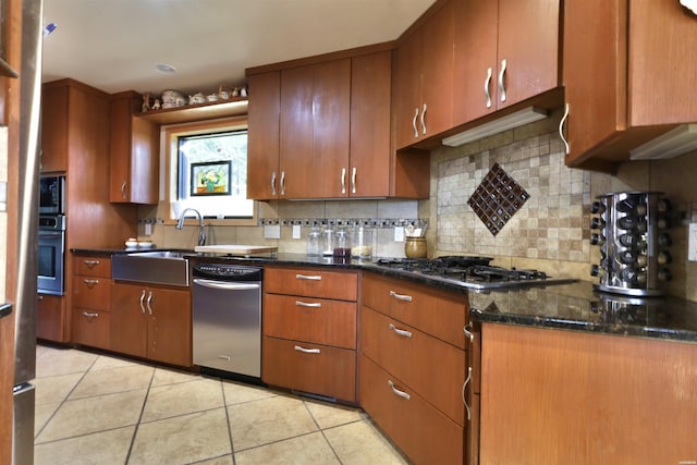 kitchen featuring light tile patterned floors, appliances with stainless steel finishes, decorative backsplash, brown cabinetry, and dark stone countertops