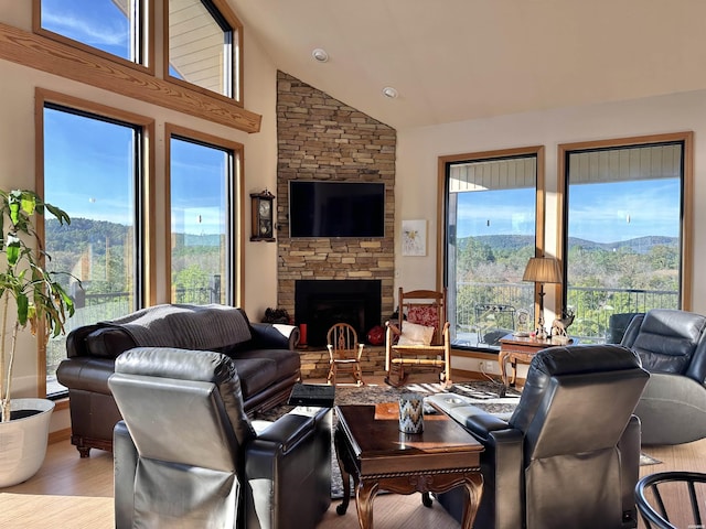 living room with high vaulted ceiling, a fireplace, and light wood-style flooring