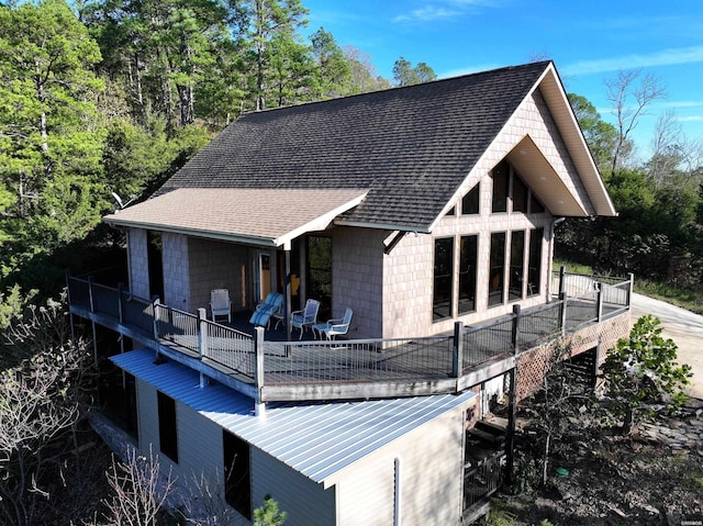 rear view of property featuring a shingled roof and a balcony