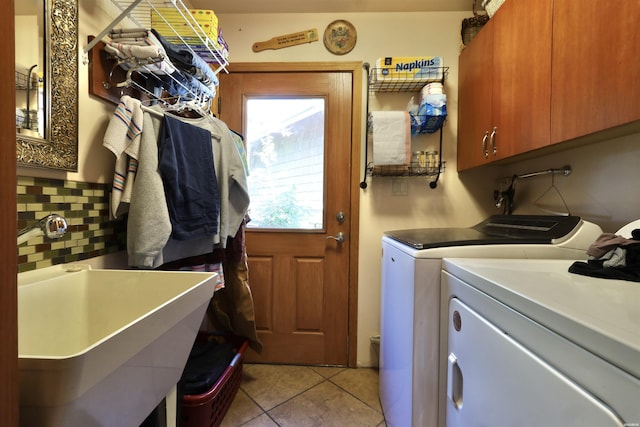 laundry area with cabinet space, washing machine and dryer, light tile patterned floors, and a sink