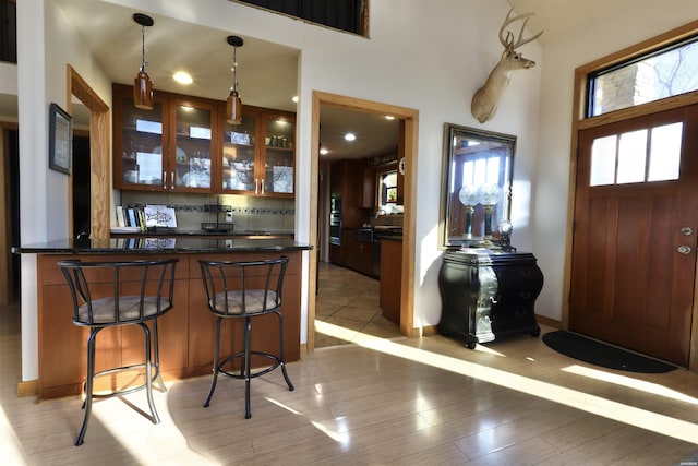 bar featuring hanging light fixtures, light wood-style flooring, stainless steel oven, and backsplash