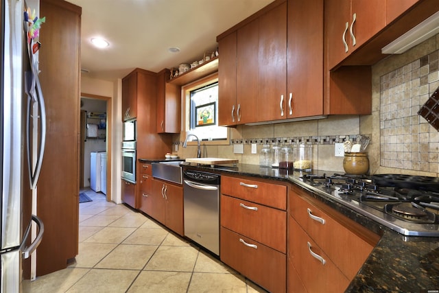 kitchen featuring light tile patterned floors, tasteful backsplash, appliances with stainless steel finishes, and dark stone countertops