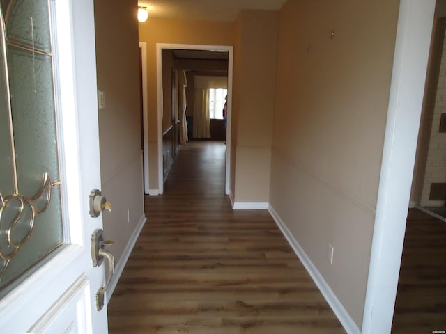 corridor with dark wood finished floors and baseboards