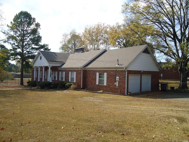 view of front of property with a garage, a front yard, a chimney, and brick siding