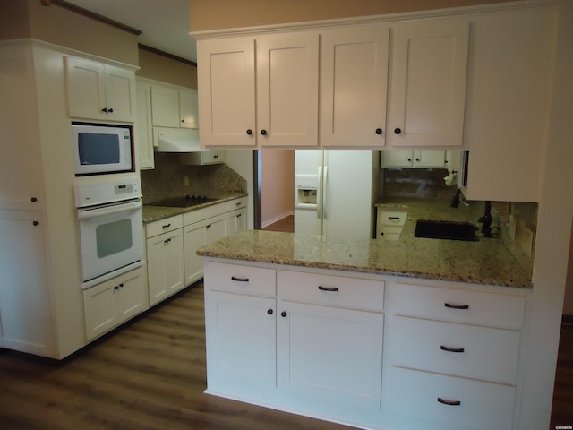 kitchen with light stone counters, white appliances, a sink, white cabinetry, and decorative backsplash