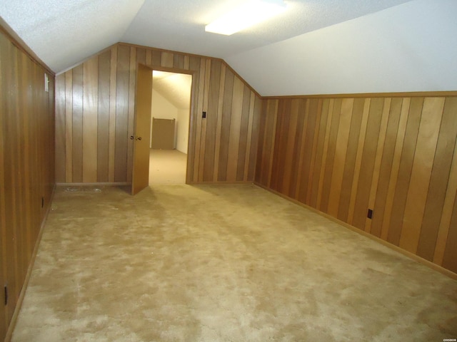 additional living space with light carpet, vaulted ceiling, and wooden walls