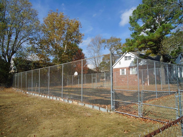 exterior space with community basketball court, fence, and a yard