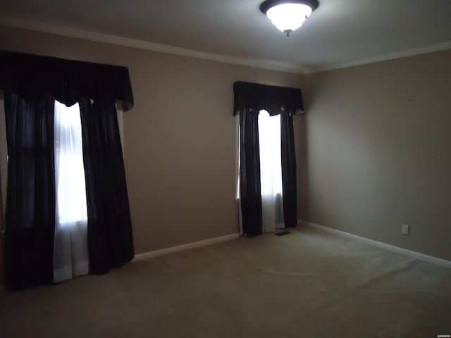 carpeted spare room featuring ornamental molding and baseboards