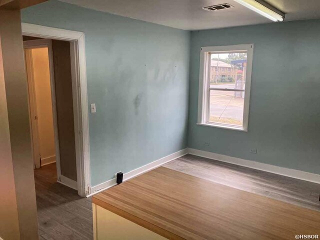 unfurnished room featuring baseboards, visible vents, and wood finished floors