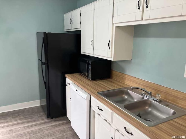 kitchen with light wood finished floors, light countertops, white cabinets, a sink, and black appliances