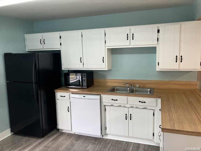 kitchen featuring black appliances, wood finished floors, a sink, and white cabinetry