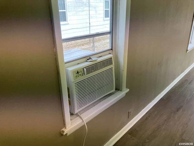 interior details featuring cooling unit, baseboards, and wood finished floors