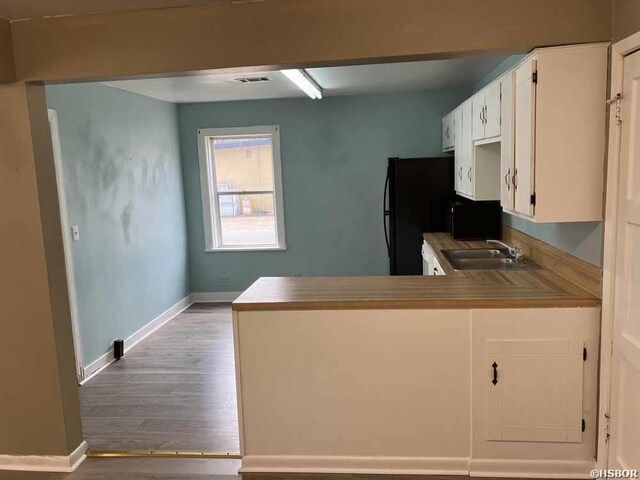 kitchen featuring a sink, a peninsula, light countertops, and white cabinets